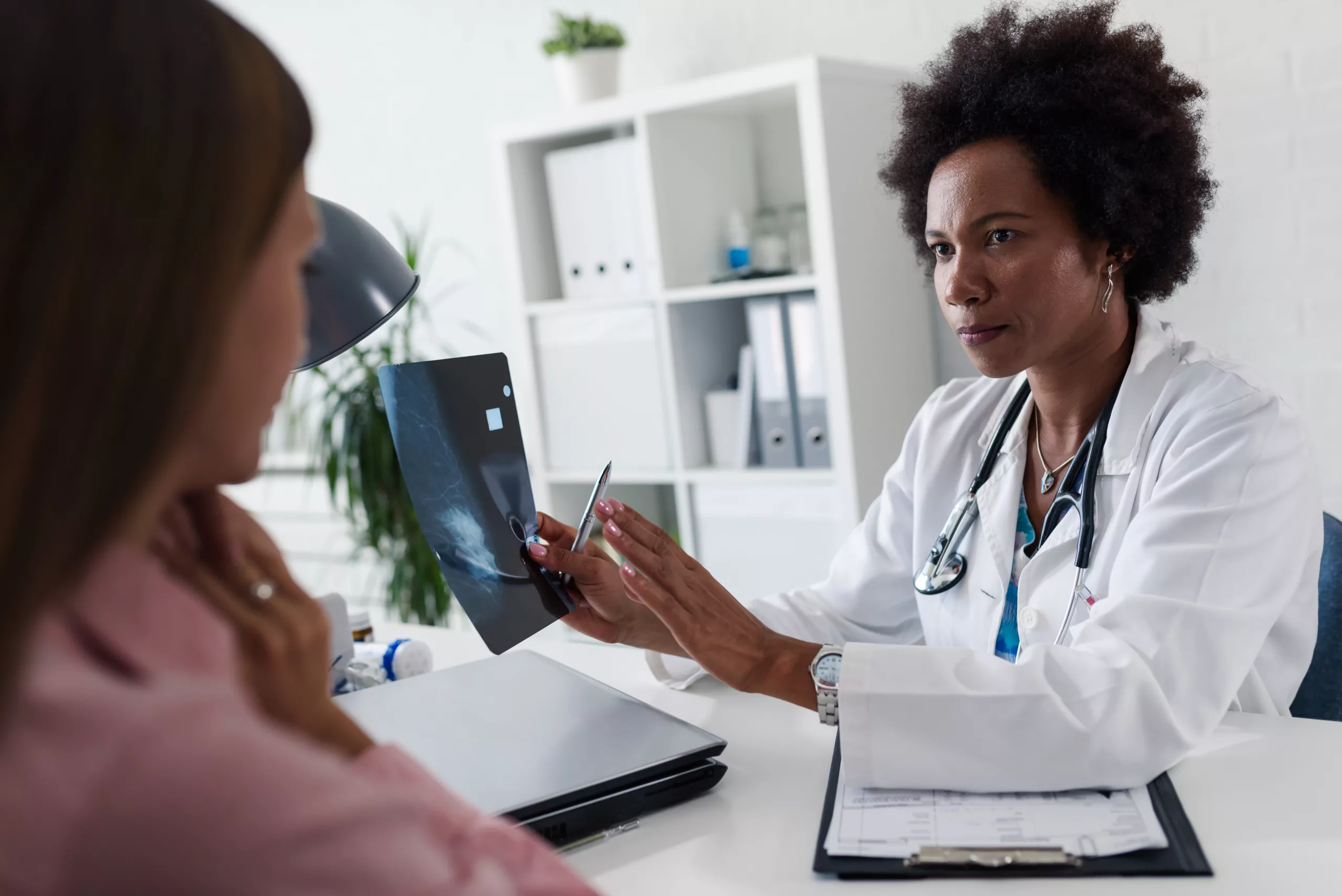 Doctor Discussing Mammogram Results with Patient Female doctor reviewing a mammogram scan with a patient in a medical office.