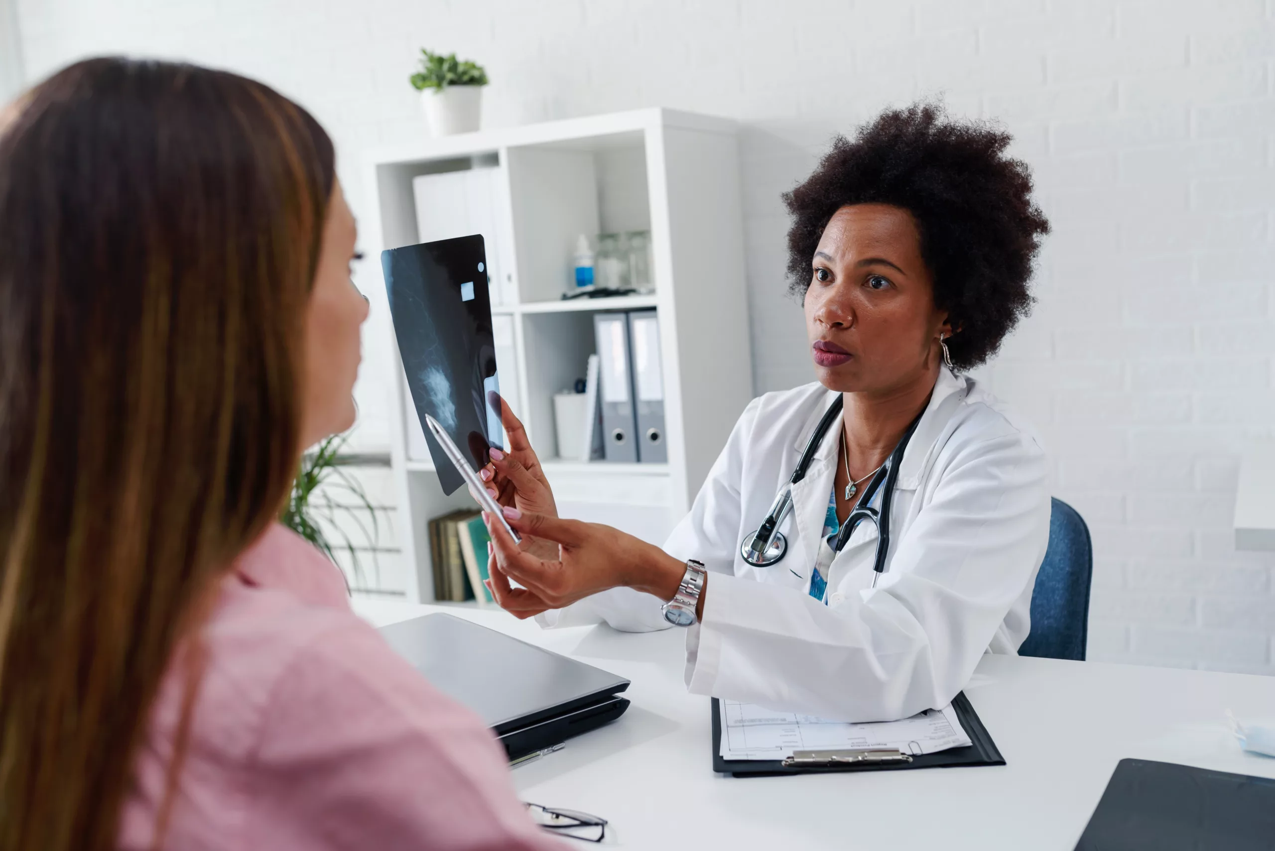 Doctor Discussing Mammogram Results with Patient A female doctor shows a mammogram image to a female patient during a medical consultation in an office.