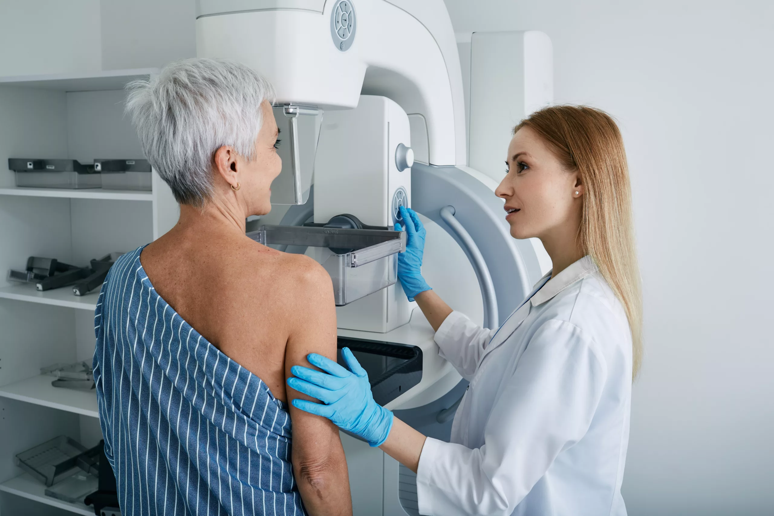 Senior woman having mammography scan at hospital with medical technician. Mammography procedure, breast cancer prevention A female doctor attentively listens to a patient during a one-on-one consultation in a medical exam room.